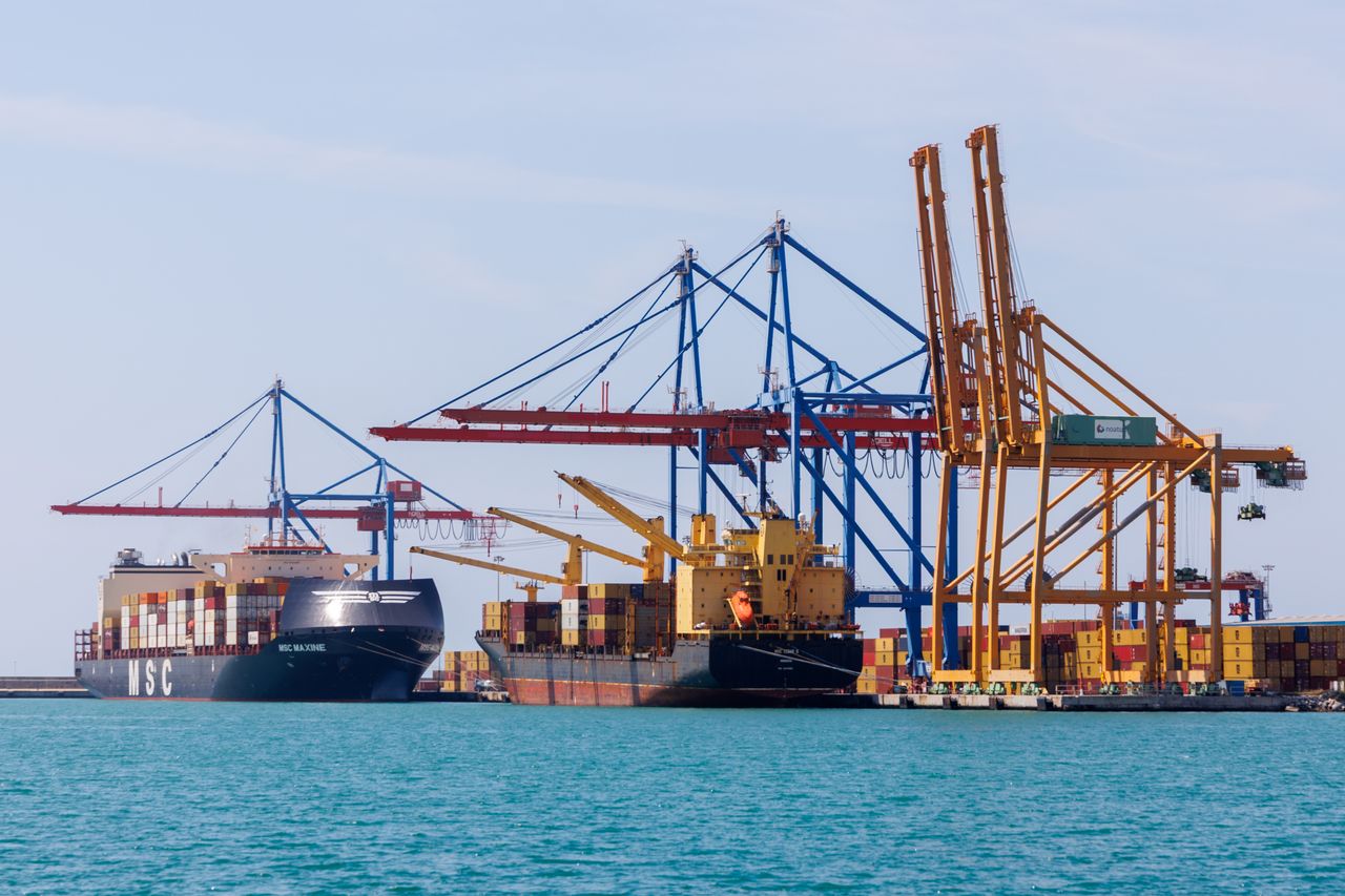 A vibrant view of Málaga's container port bustling with cranes and cargo ships during the day.